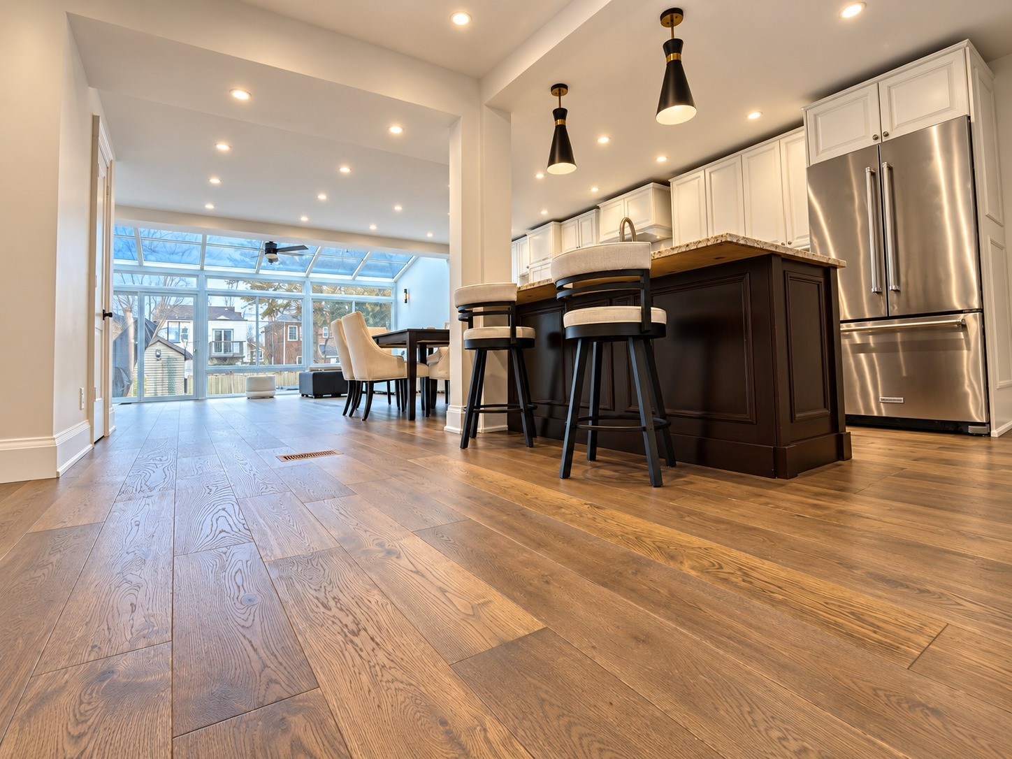 Finished residential hardwood flooring installation with wide wood planks throughout an open-concept kitchen and living area