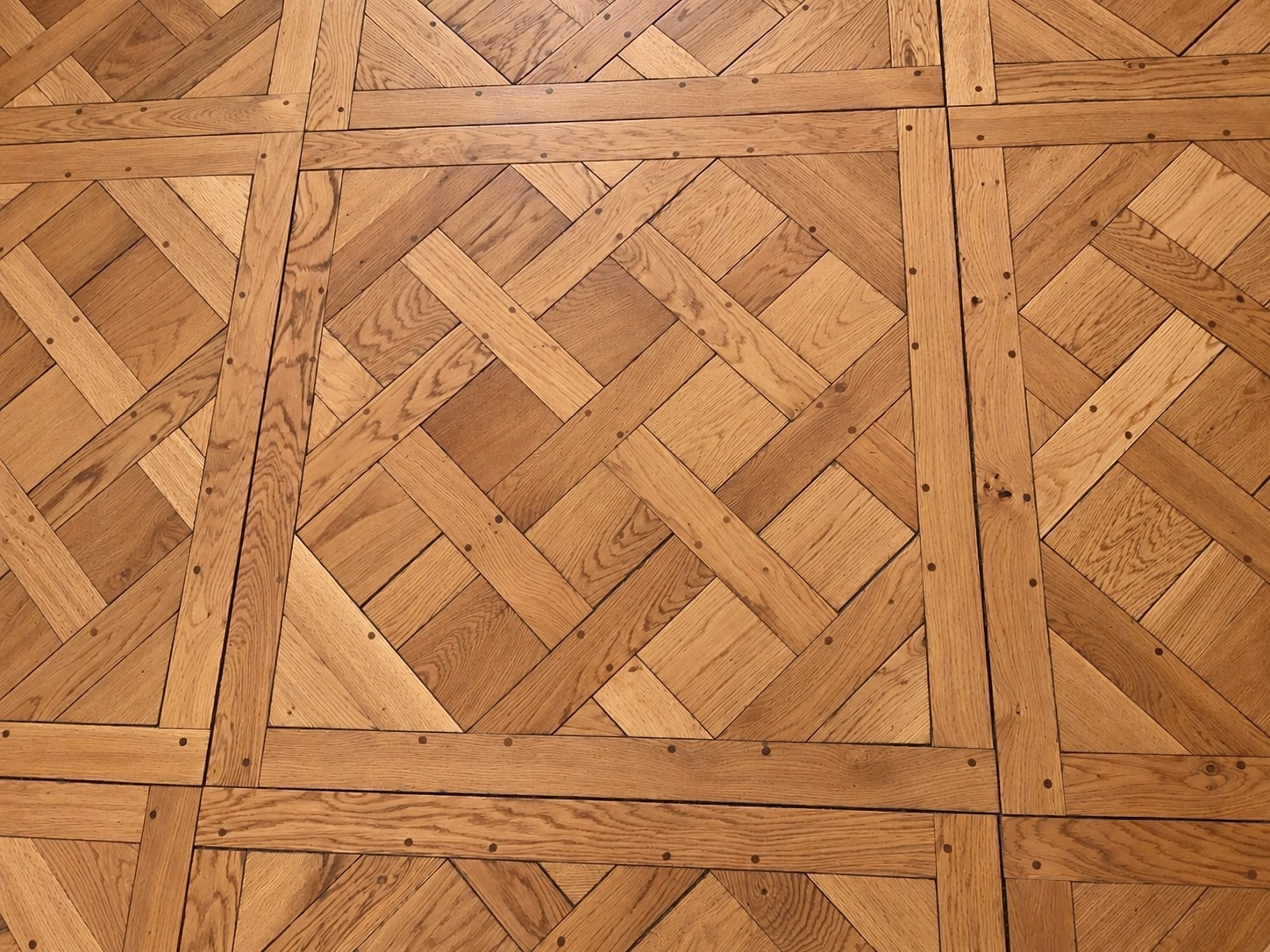 Geometric hardwood floor pattern with contrasting wood borders and detailed custom inlay work